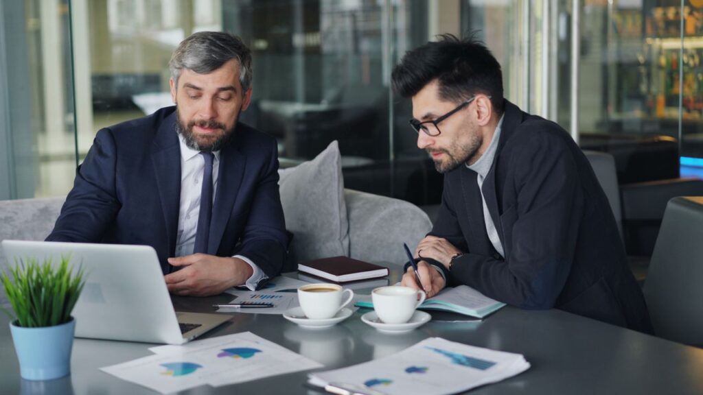 Two businessmen in suits reviewing charts and graphs for company bookkeeping